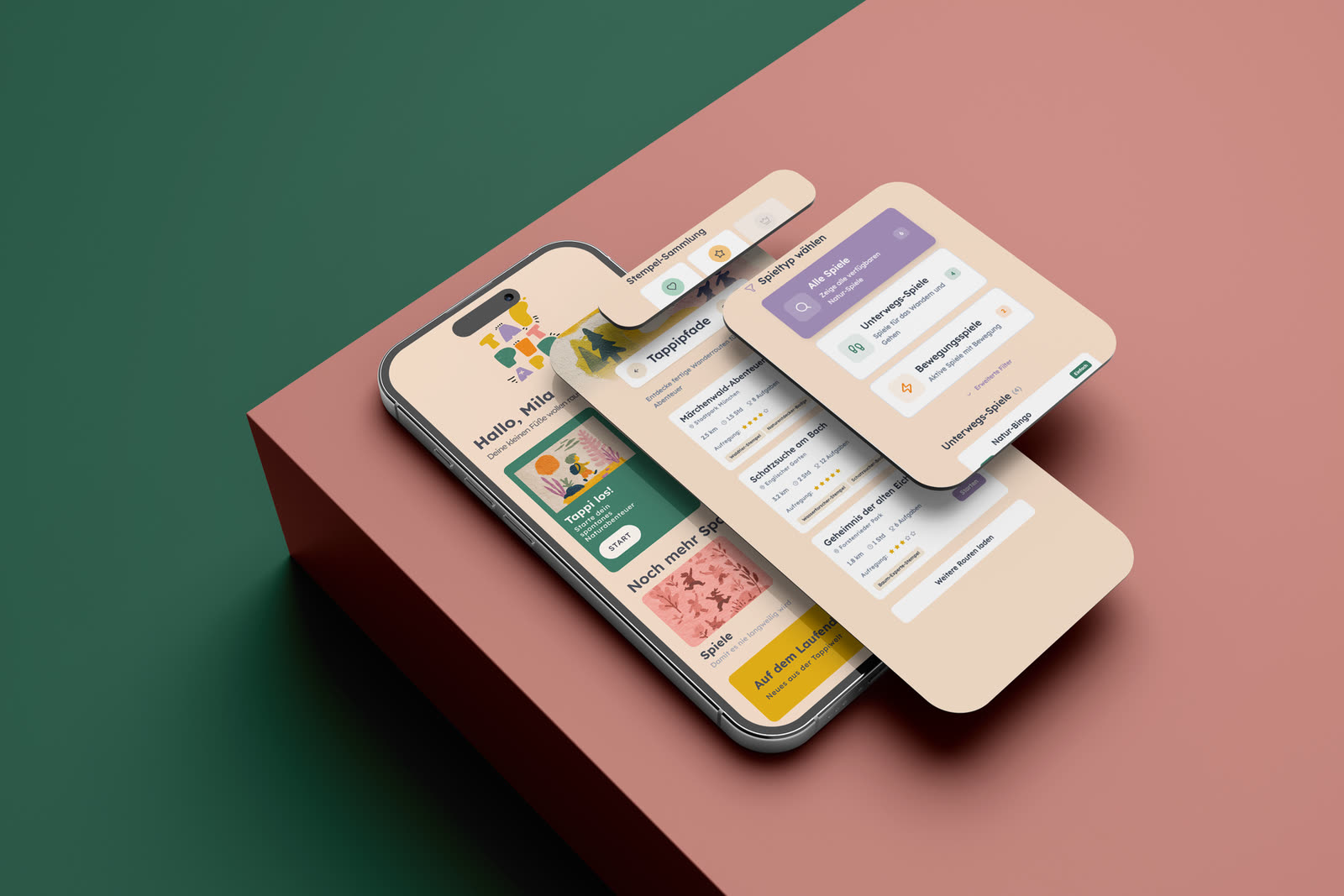 Drei Screens der Kinder-App TappiTapp auf einem Smartphone, gestapelt über einer roséfarbenen Fläche: die Startseite begrüßt „Hallo, Mila“, daneben die geplanten Tappipfade und die Auswahl der Naturspiele.